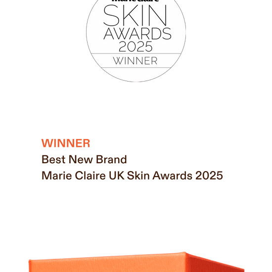 Award graphic for the Marie Claire UK Skin Awards 2025, showing a white circular badge at the top and text reading 'Winner Best New Brand Marie Claire UK Skin Awards 2025' on a dark green background, with part of an orange product box visible at the bottom.