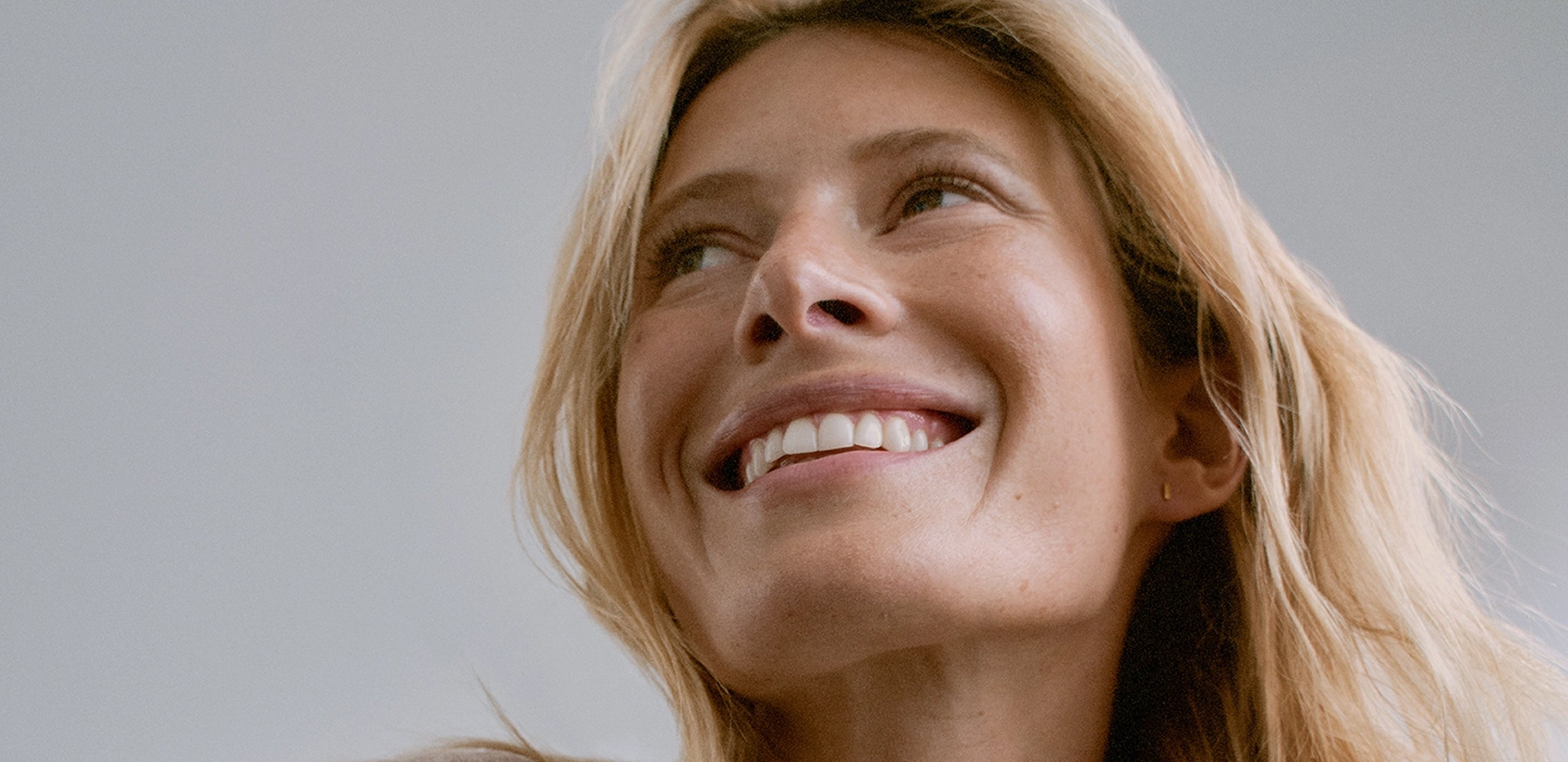 Woman with blonde hair smiling against a plain background
